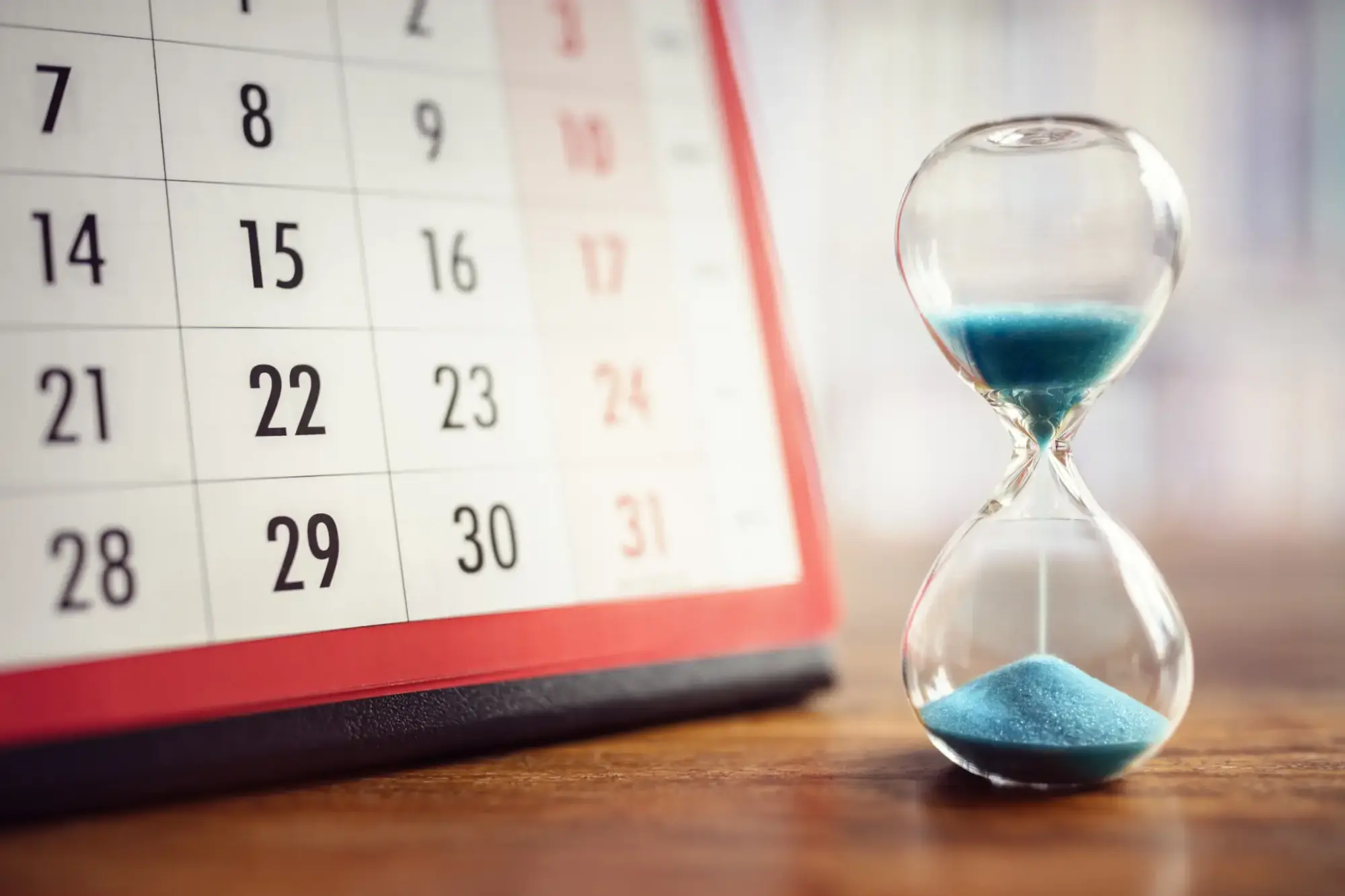 Hourglass And Calendar Hour glass and calendar concept for time slipping away for important appointment date, schedule and deadline