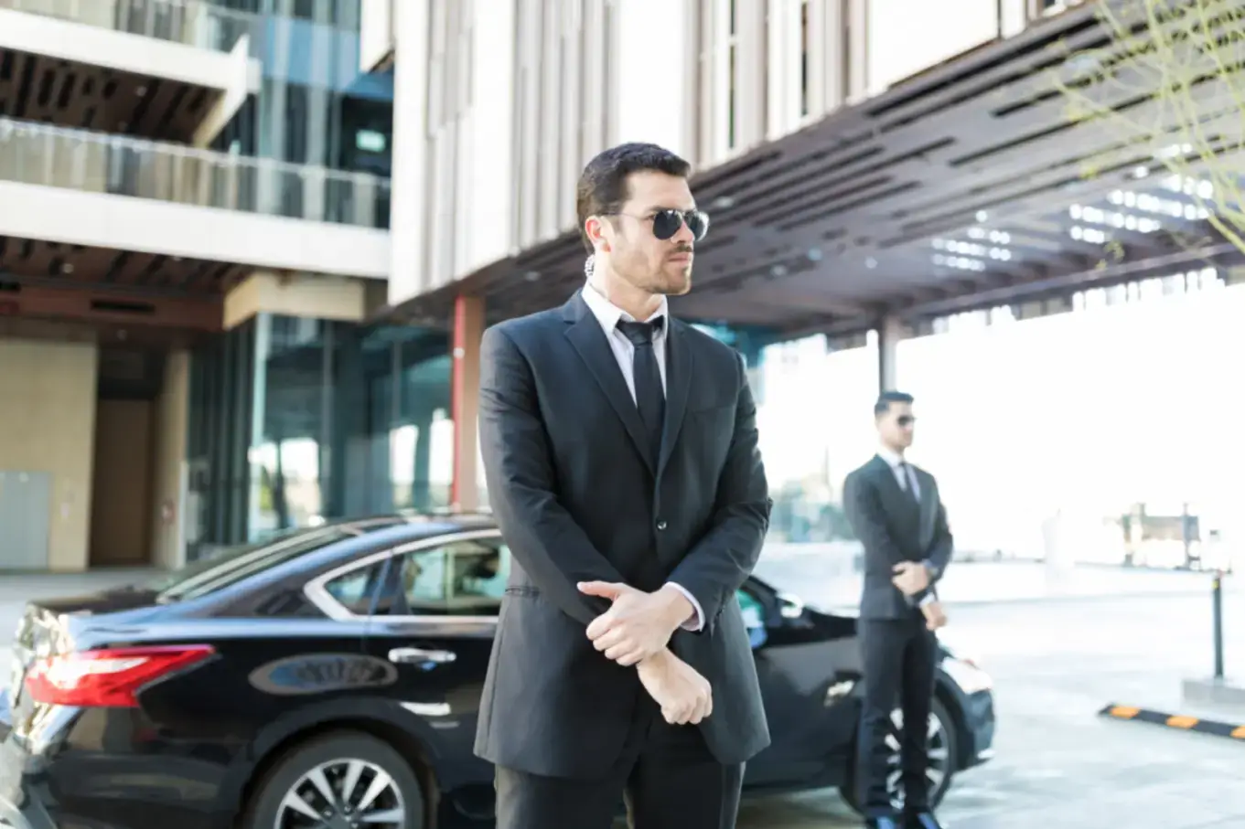 Responsible Bodyguards Doing Their Duties Alert bodyguard keeping an eye on surroundings with car parked on city street