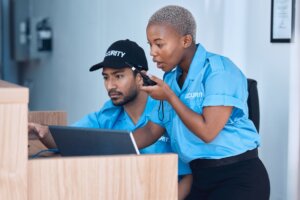 Two unarmed security guards analyze footage while on the job.
