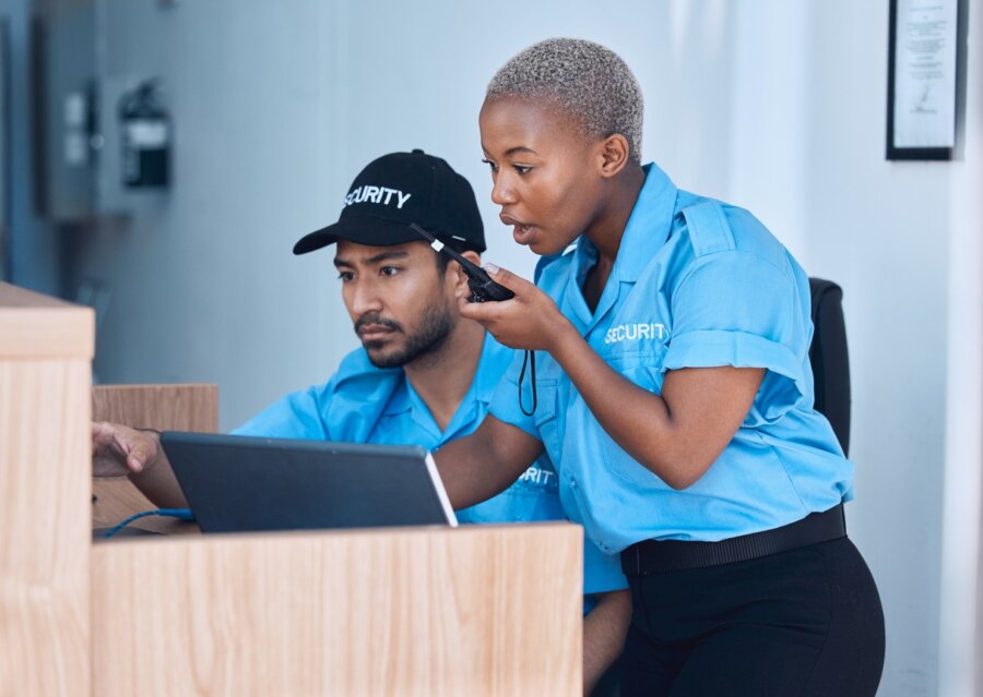 Two unarmed security guards analyze footage while on the job.