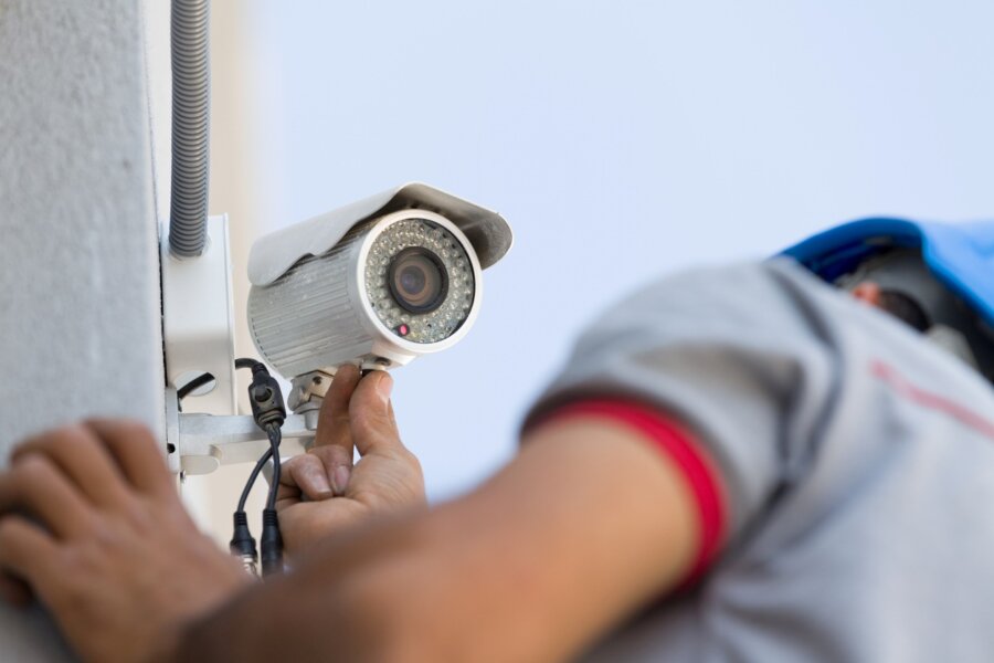 A technician installs an outdoor security camera