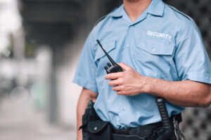 Security officer in uniform holding a two-way radio at a commercial property.